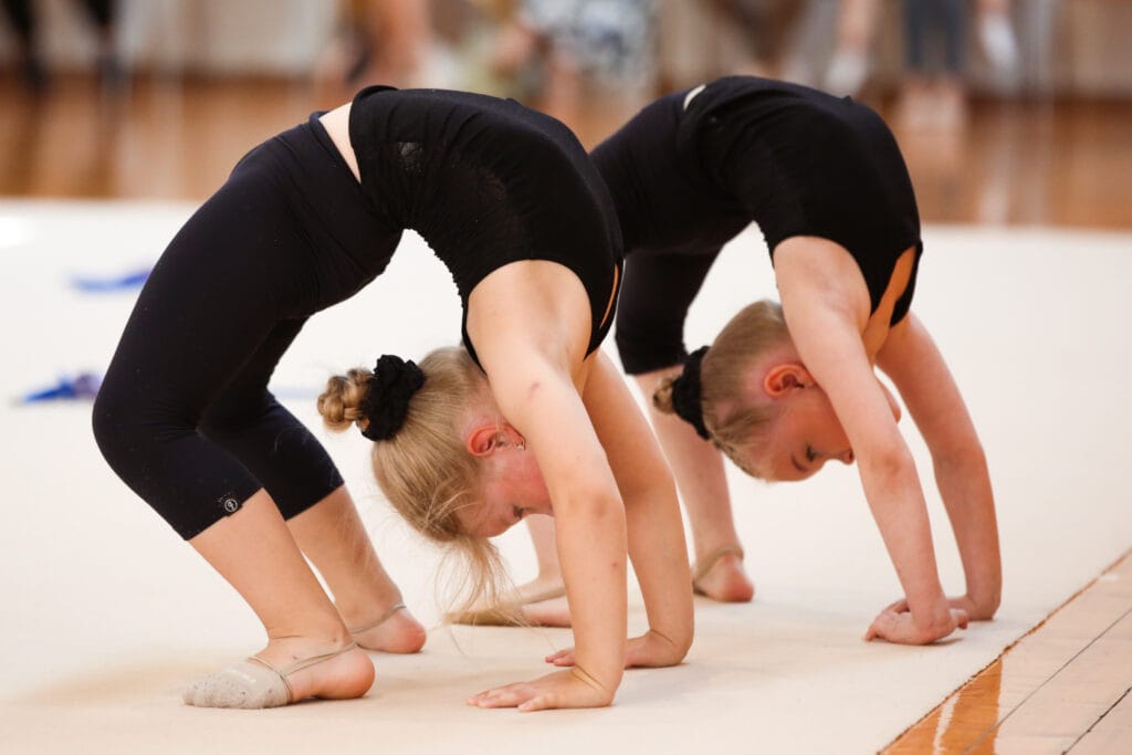 Noored võimlejad sooritamas silda võistlusmatil – painduvust ja jõudu arendav harjutus.