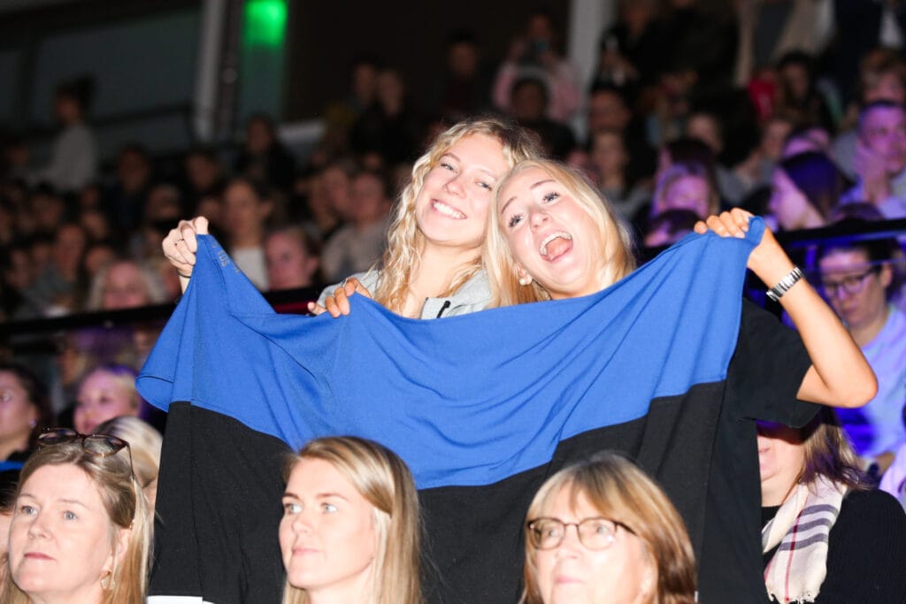 Iluvõimlemise fännid tribüünil rõõmsalt kaasa elamas, lehvitamas Eesti lippu.