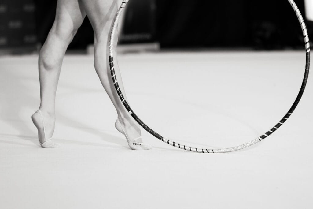Iluvõimleja sooritamas rõngakava – detailikaader jalgade tööst ja võimlemisrõngast võistlusmatil.